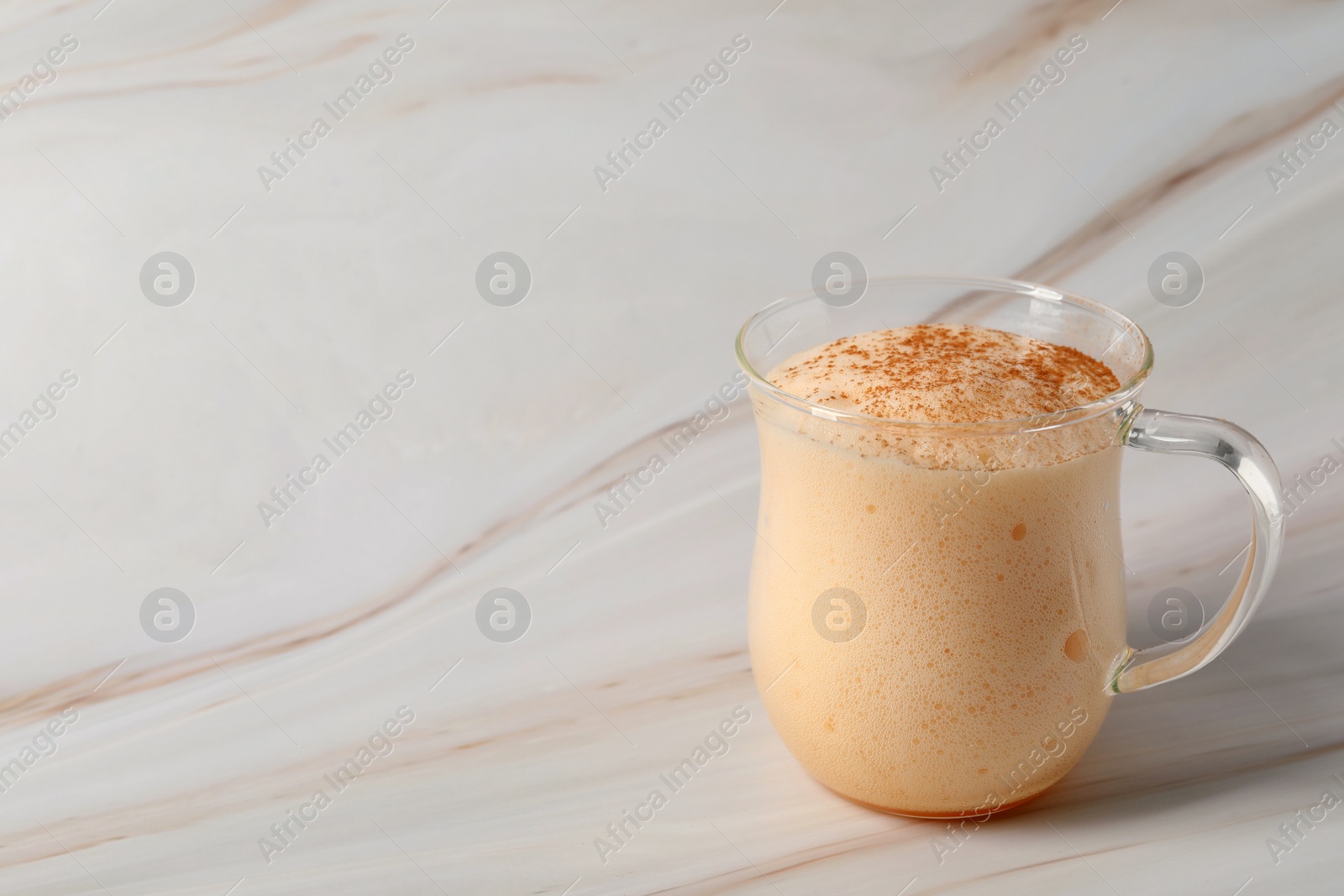 Photo of Delicious eggnog on white marble table. Space for text