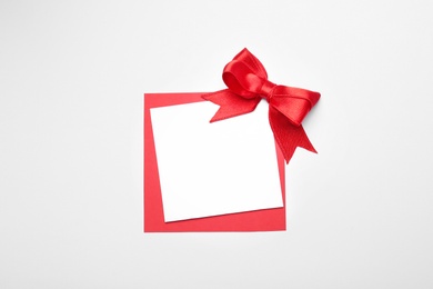 Photo of Blank gift tag with satin ribbon on white background, top view