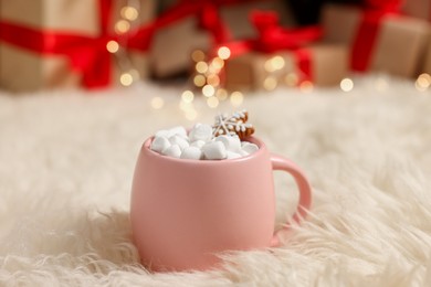 Photo of Christmas cocoa with marshmallows and gingerbread cookie in pink cup on soft carpet indoors, closeup