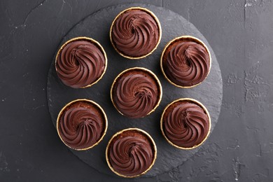 Delicious chocolate cupcakes on black textured table, top view