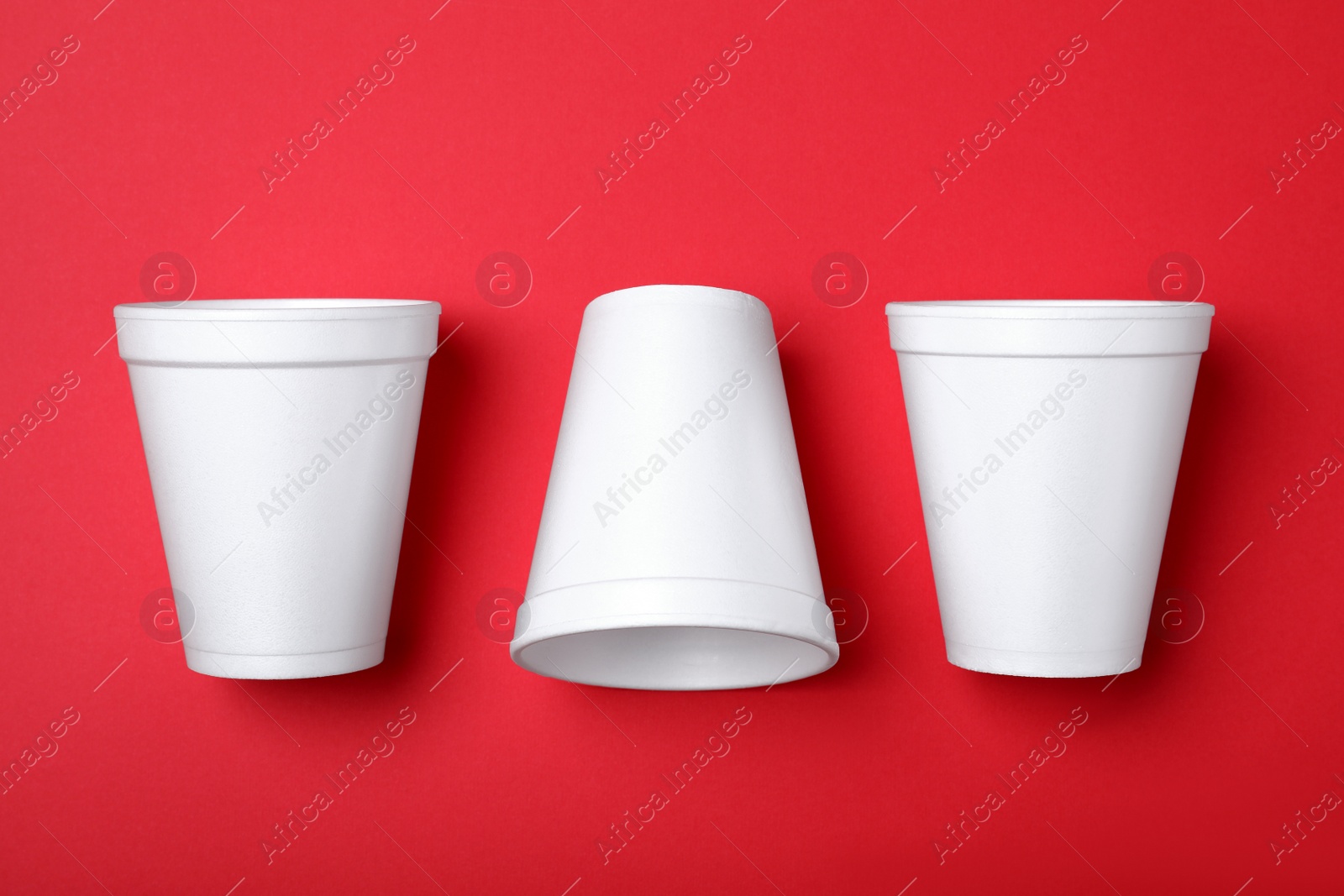 Photo of White styrofoam cups on red background, flat lay