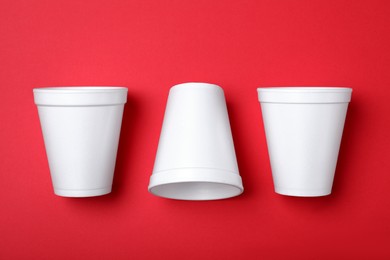 Photo of White styrofoam cups on red background, flat lay