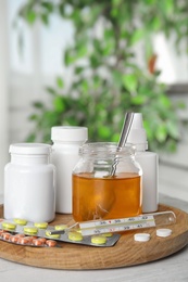Honey and different cold remedies on white wooden table