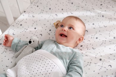 Photo of Adorable happy baby with toy lying in crib