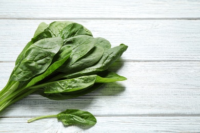 Fresh green healthy spinach on white wooden table. Space for text