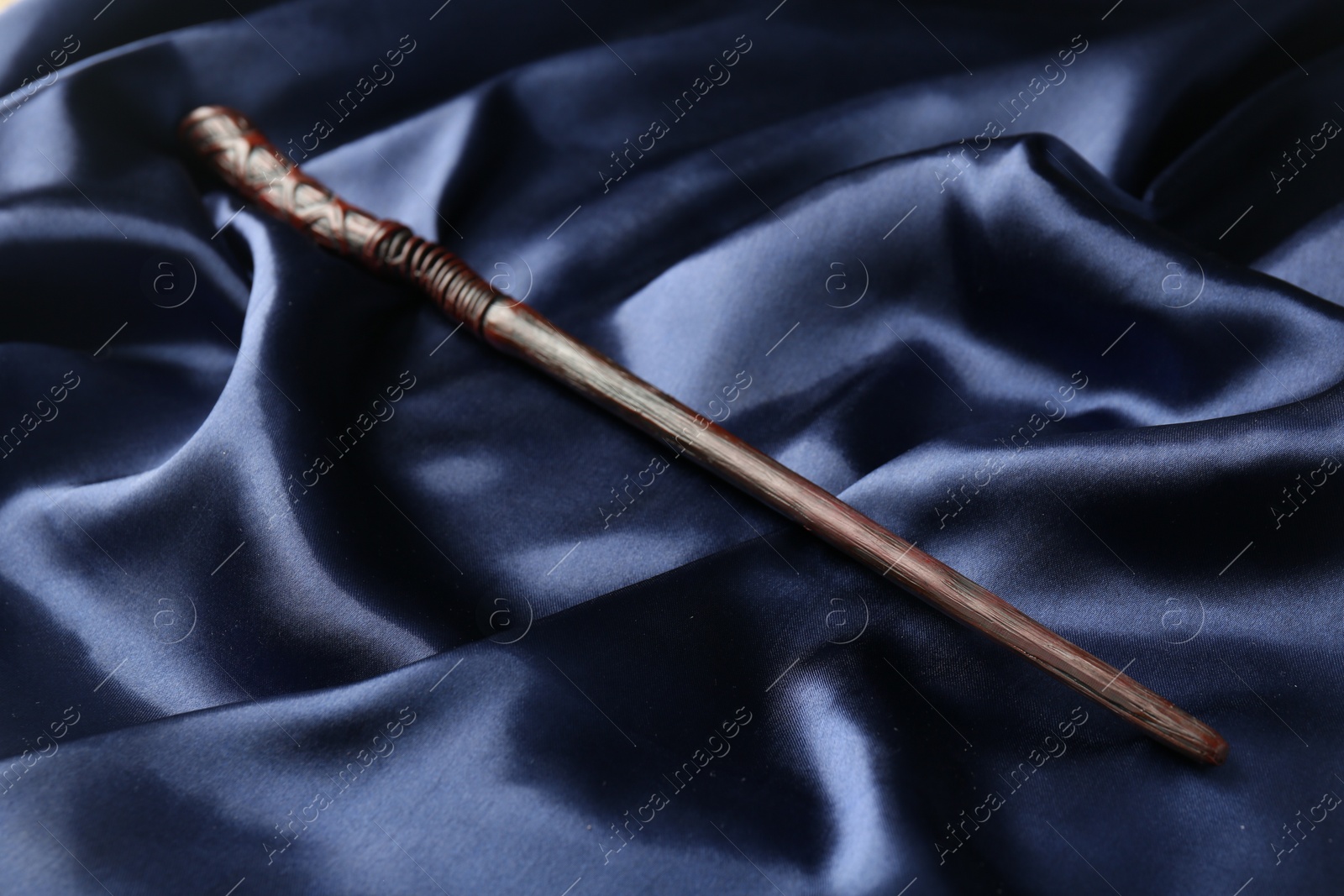 Photo of Old wooden magic wand on dark blue silk