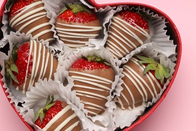 Heart shaped box with delicious chocolate covered strawberries on pink background, top view