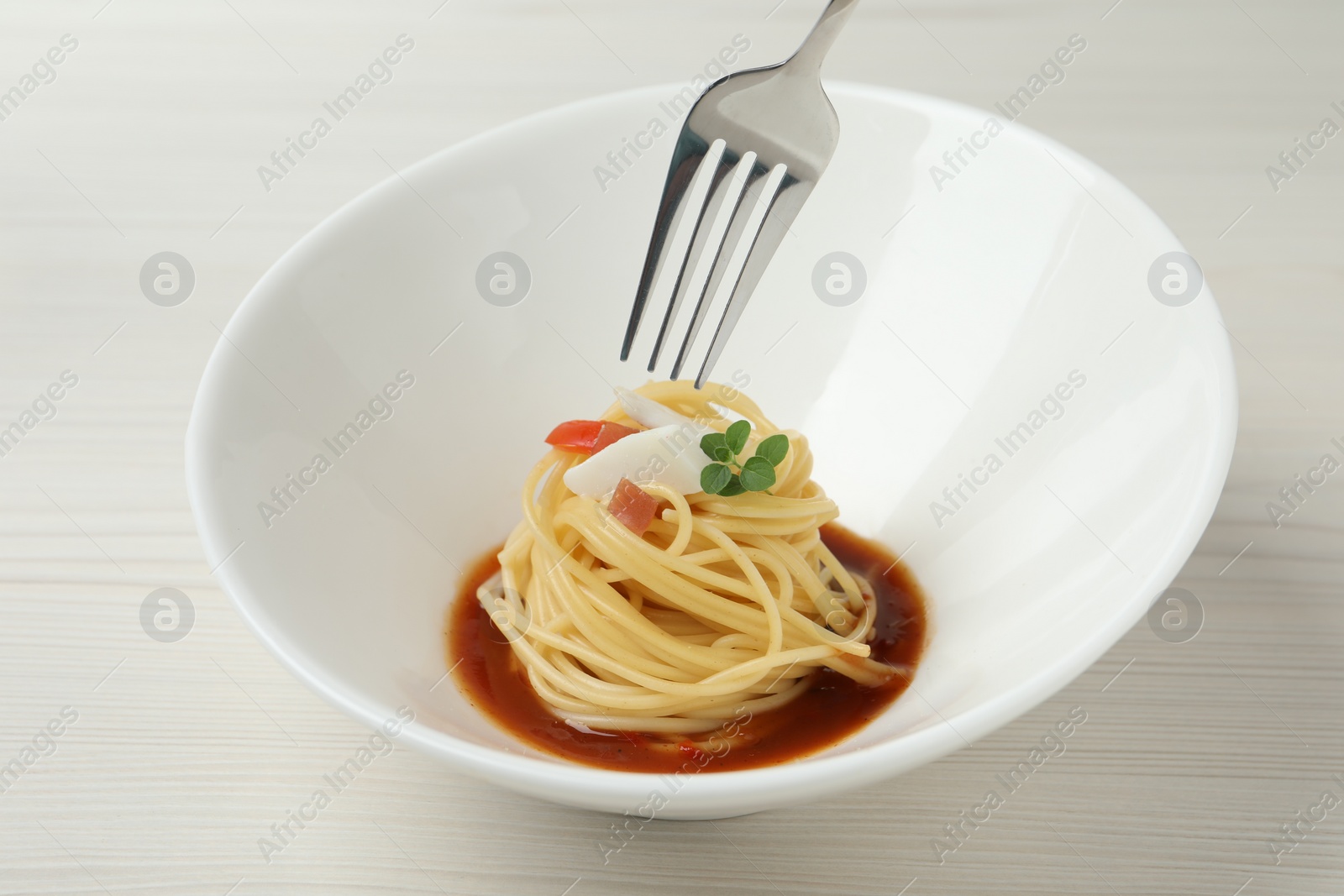Photo of Eating tasty spaghetti with sauce from at white wooden table, closeup. Exquisite presentation of pasta dish