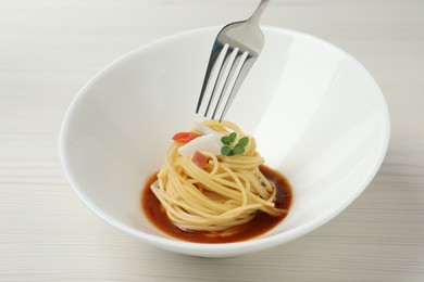 Eating tasty spaghetti with sauce from at white wooden table, closeup. Exquisite presentation of pasta dish