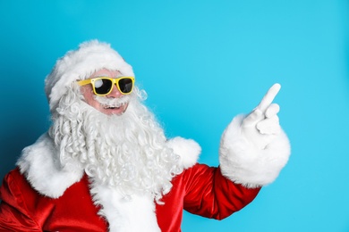 Authentic Santa Claus wearing sunglasses on color background