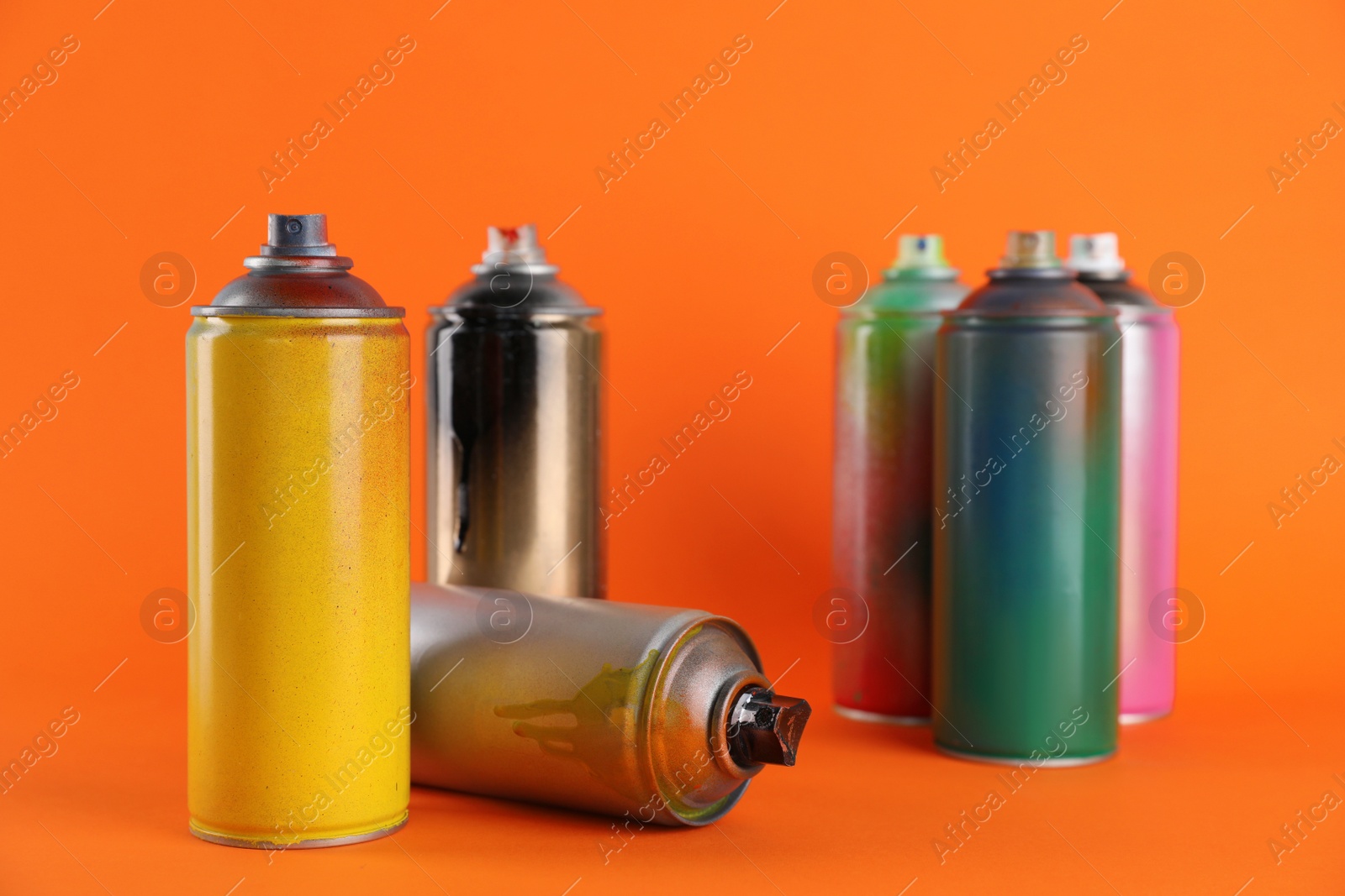 Photo of Used cans of spray paints on orange background