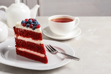 Photo of Plate with piece of delicious homemade red velvet cake on table. Space for text