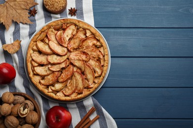 Photo of Delicious apple pie and ingredients on blue wooden table, flat lay. Space for text