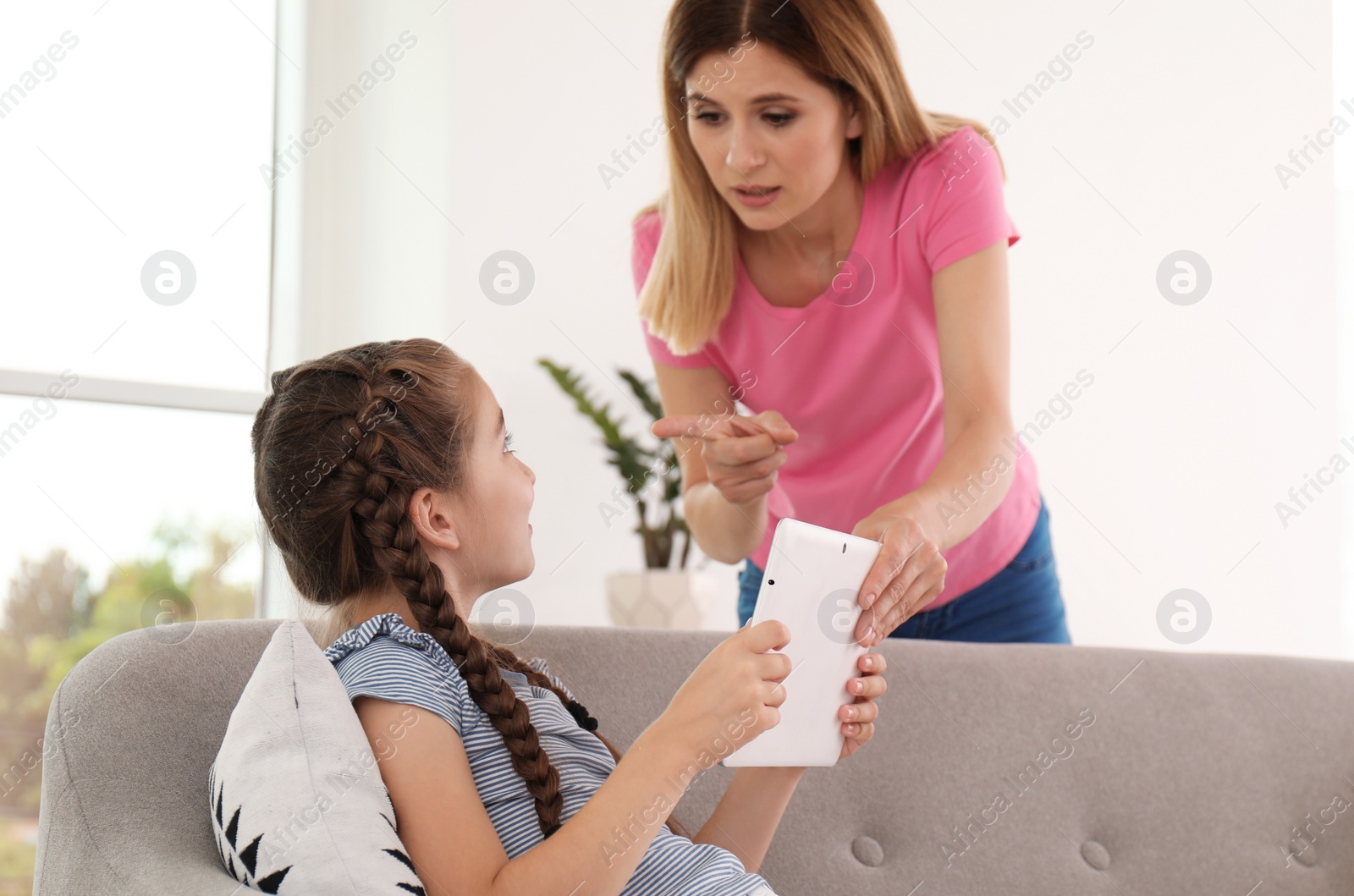 Photo of Mother taking tablet from child at home. Family problems