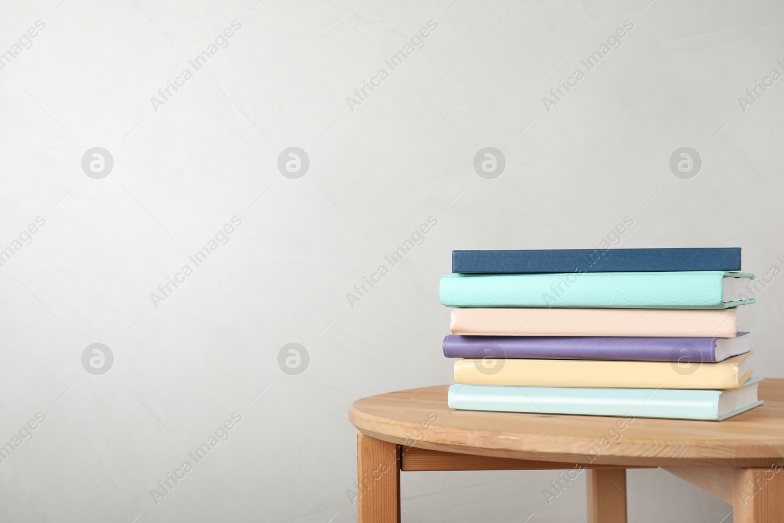 Photo of Stack of books on table against light background. Space for text