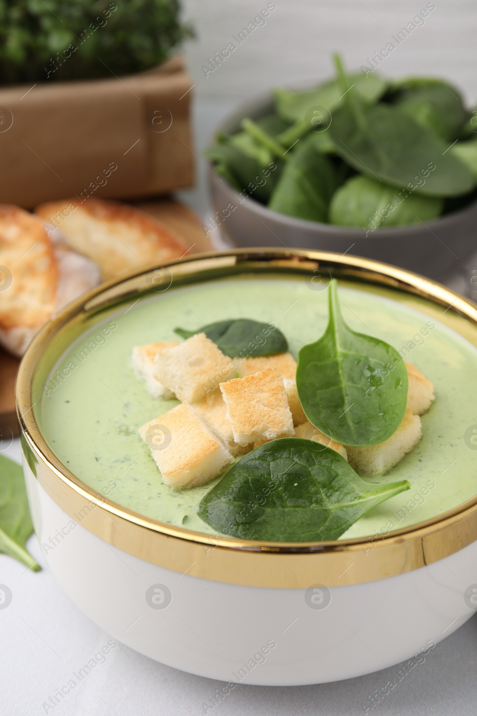 Photo of Delicious spinach cream soup with croutons in bowl on table, closeup