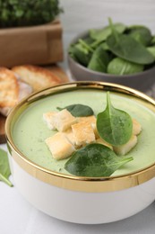 Delicious spinach cream soup with croutons in bowl on table, closeup