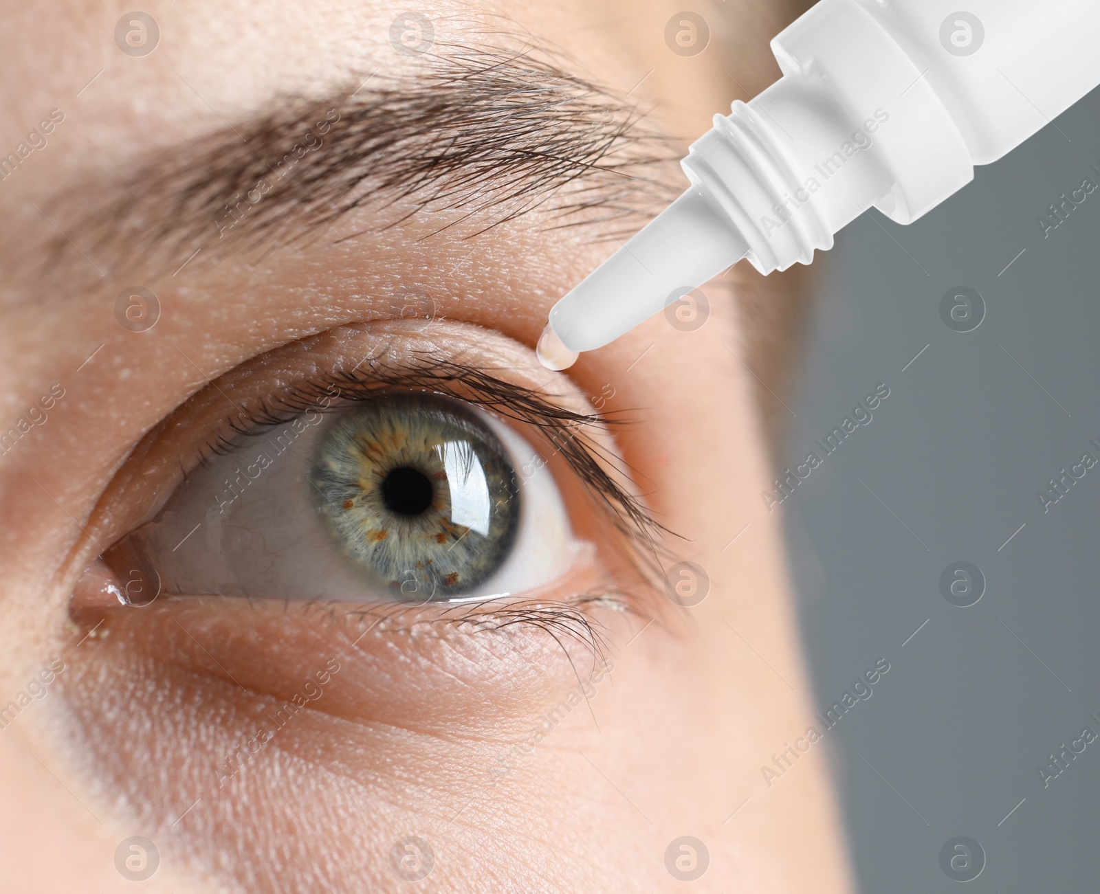 Image of Man applying eye drops on grey background, closeup