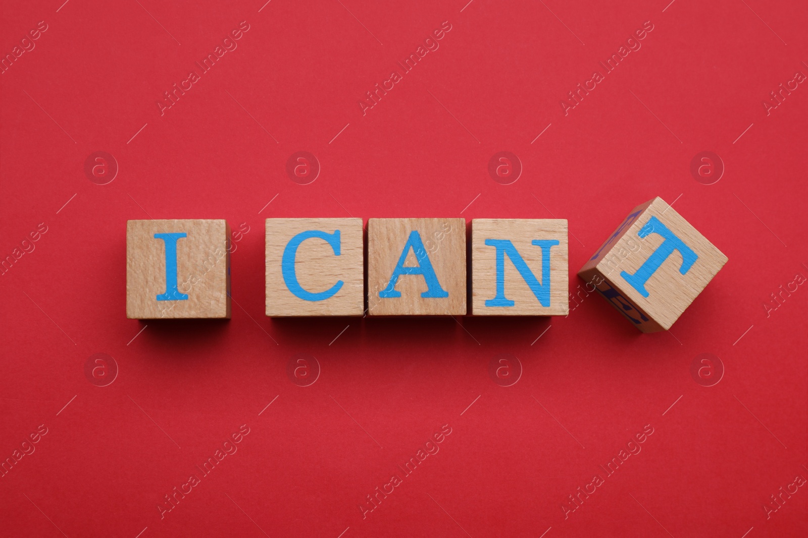 Photo of Motivation concept. Changing phrase from I Can't into I Can by removing wooden cube with letter T on red background, flat lay
