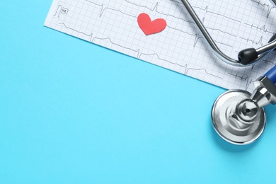 Photo of Cardiogram report, red paper heart and stethoscope on light blue background, flat lay with space for text
