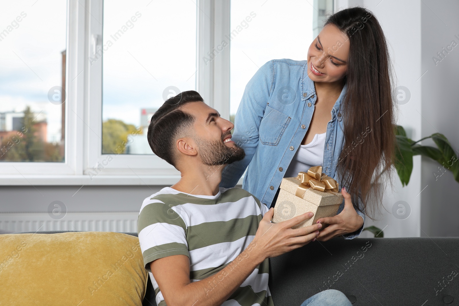 Photo of Woman presenting gift to her boyfriend at home