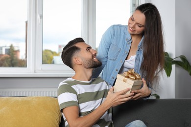 Photo of Woman presenting gift to her boyfriend at home
