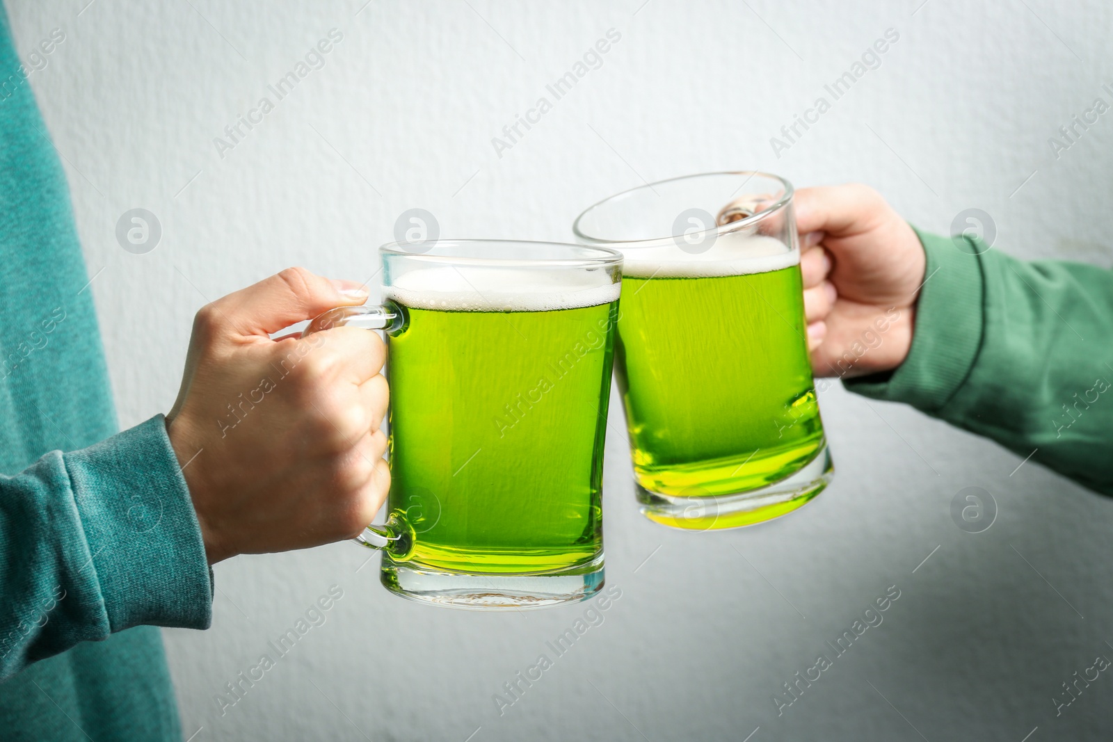 Photo of Man and woman toasting with green beer on white background, closeup. St. Patrick's Day celebration