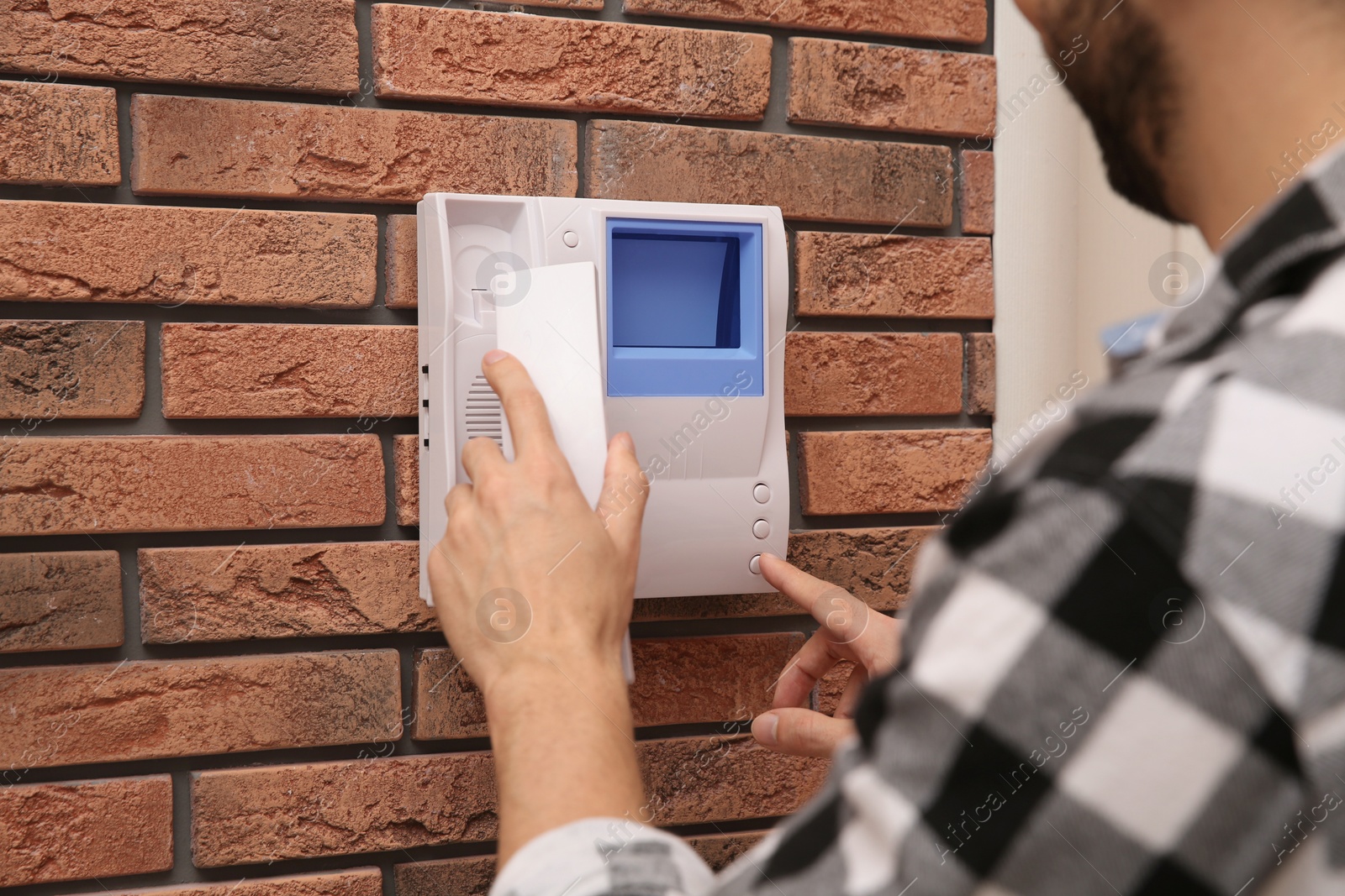 Photo of Man pressing button on intercom panel indoors, closeup