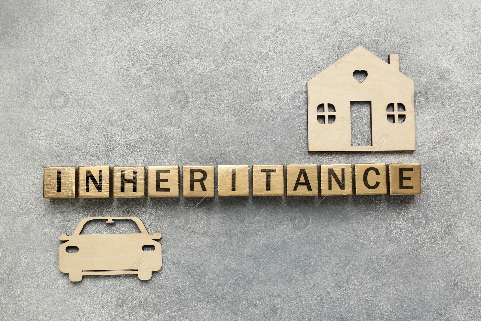 Photo of Word Inheritance made with wooden cubes, house and car models on grey background, flat lay
