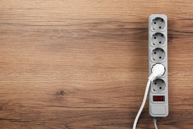 Photo of Power strip with extension cord on wooden floor, top view. Space for text