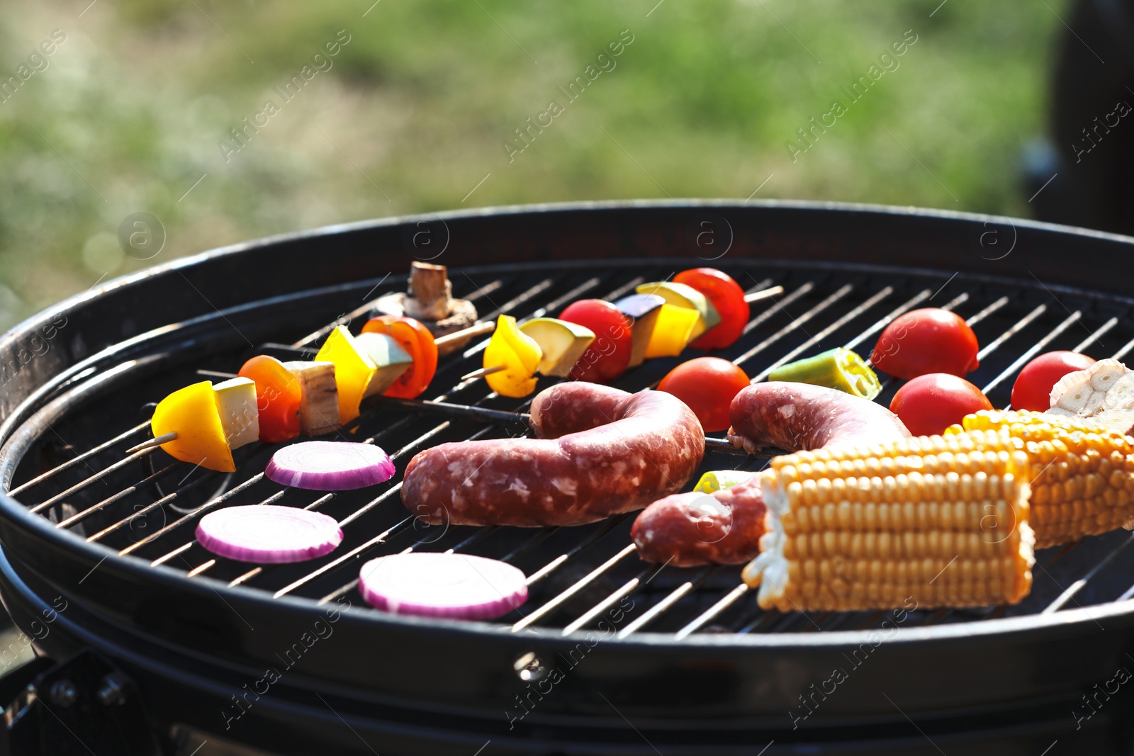 Photo of Tasty sausages and vegetables on modern barbecue grill outdoors, closeup