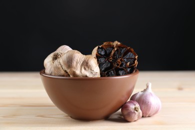 Bulbs of fresh and fermented black garlic on wooden table