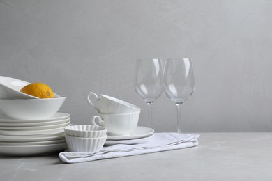 Photo of Set of clean dishware, glasses and lemon on light grey table