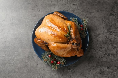 Platter of cooked turkey with cranberry and fir tree branches on grey background, top view