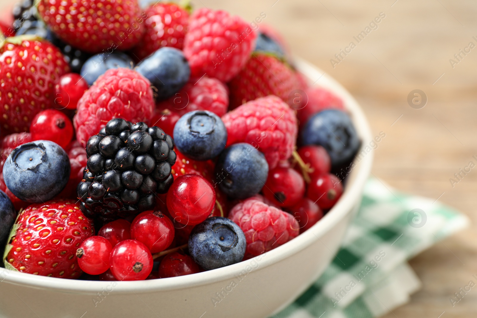 Photo of Mix of ripe berries in bowl on table, closeup