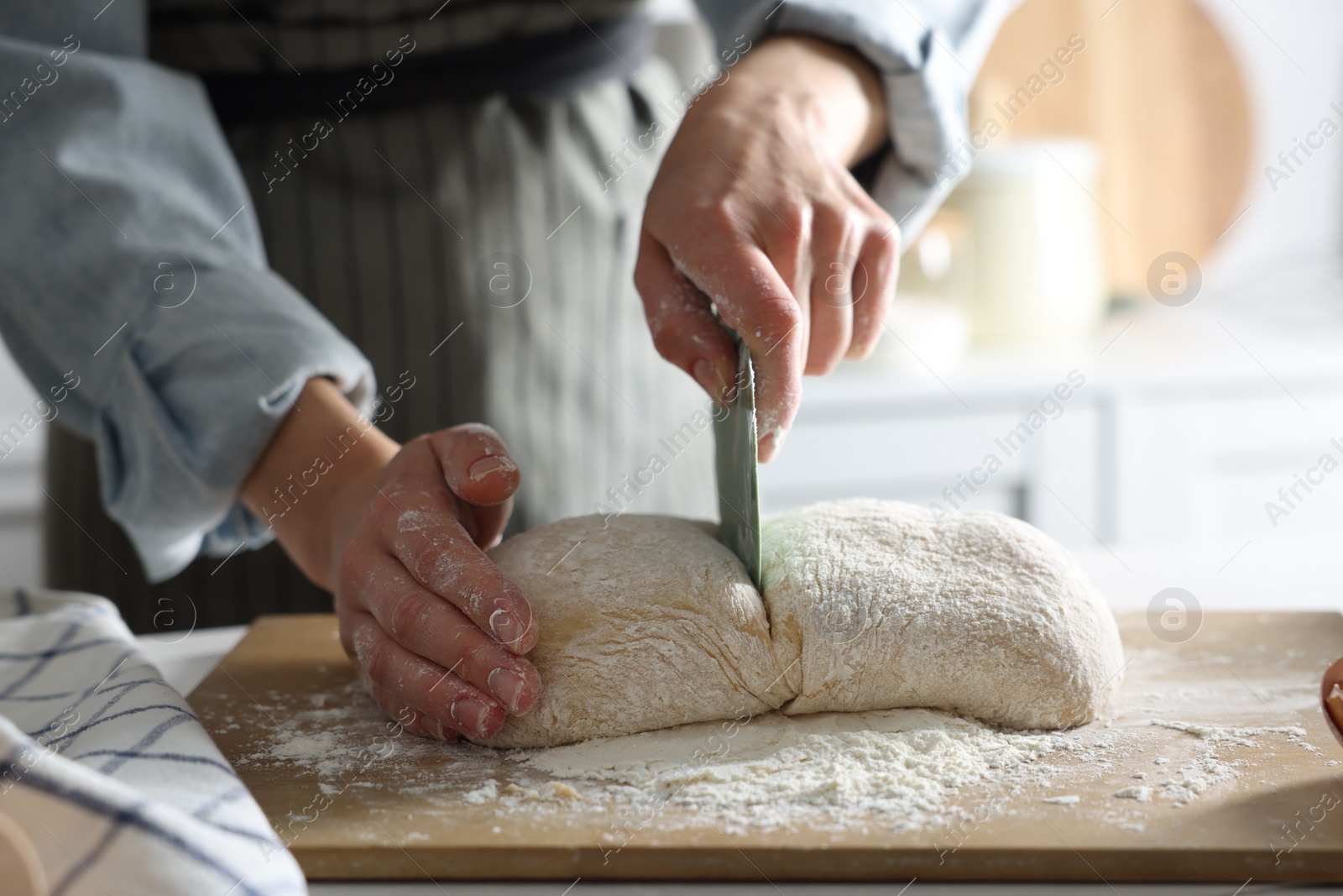 Photo of Woman cutting dough at white wooden table in kitchen, closeup