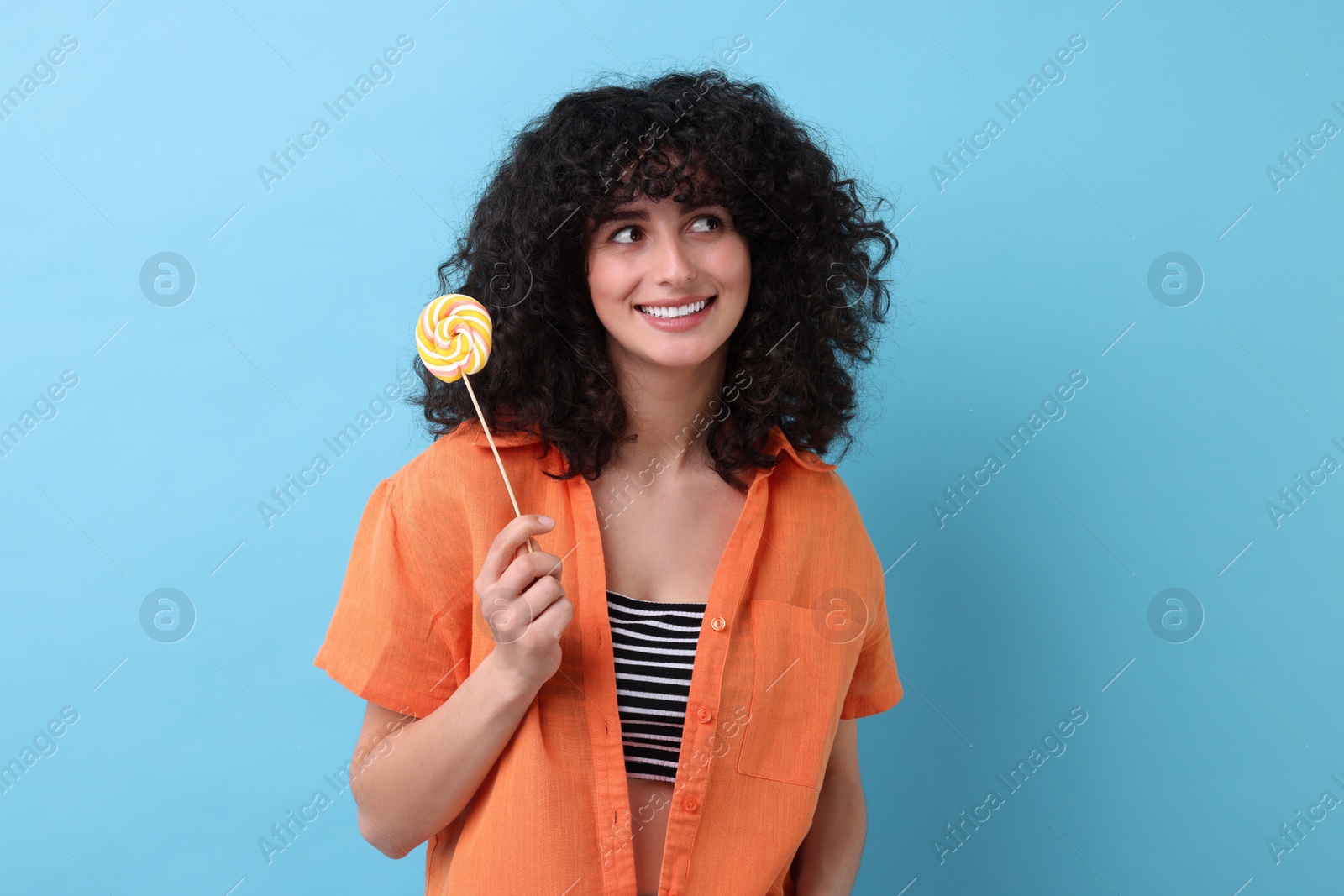 Photo of Beautiful woman with lollipop on light blue background