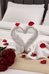 Photo of Honeymoon. Swans made of towels and beautiful red roses on bed