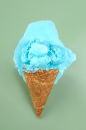 Melted ice cream and wafer cone on green background, top view