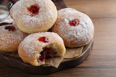 Photo of Delicious donuts with jelly and powdered sugar on wooden table, closeup