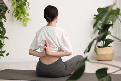 Photo of Girl practicing vajrasana with namaste behind back on mat in yoga studio