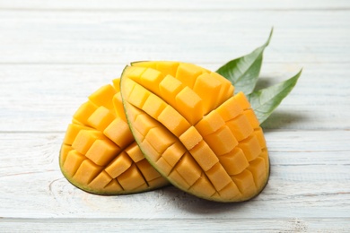 Cut ripe mango on white wooden background