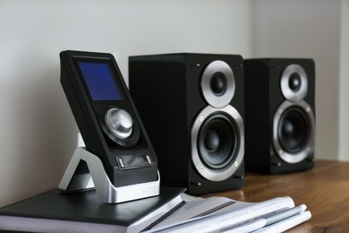 Photo of Modern powerful audio speakers and remote on table indoors