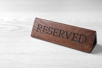 Photo of Elegant wooden sign RESERVED on white table, space for text