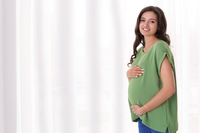 Photo of Beautiful pregnant woman near window at home