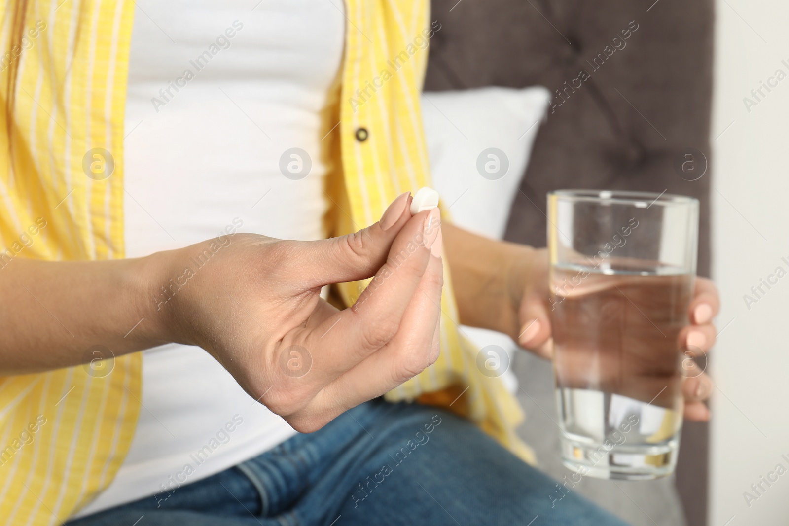 Photo of Woman with pill and glass of water indoors, closeup