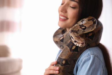 Photo of Woman with her boa constrictor at home, closeup. Exotic pet