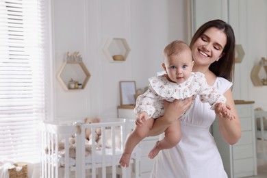 Photo of Happy young mother with her baby daughter in nursery. Space for text