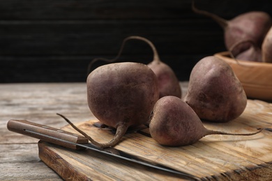 Wooden board with ripe beets on table