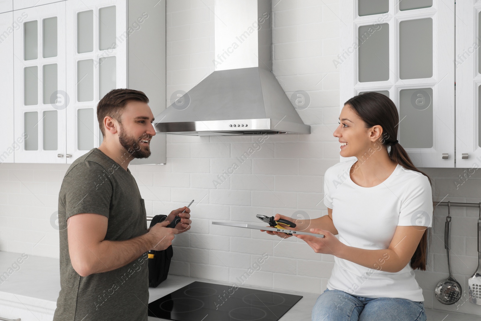 Photo of Woman giving filter of cooker hood to man in kitchen